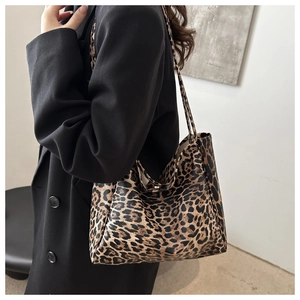 Close-up side view of leopard print tote bag styled with a professional black blazer