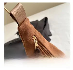 Detail of premium brown suede bag featuring a smooth metal zipper and nylon shoulder strap