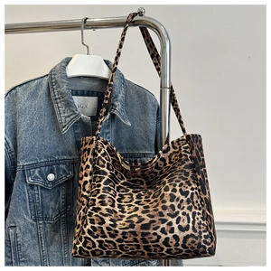 Close-up of leopard print tote bag hanging on a rack with denim jacket accent