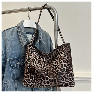 Detail of leopard print tote bag hanging next to a denim jacket in a lifestyle setting