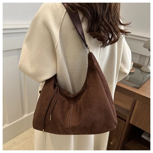 Dettaglio borsa tote in pelle scamosciata marrone con cuciture bianche e nappa