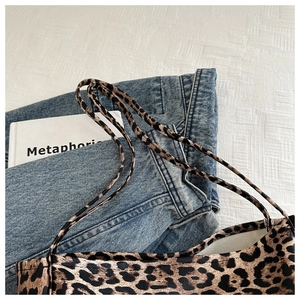 Detail of leopard print tote bag with multiple thin straps on a casual denim background