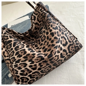 Detailed close-up of the leopard print faux leather texture and shoulder strap on the tote