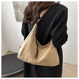 Close-up of khaki suede hobo bag with drawstring detail on a black blazer