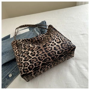 Detail of trendy leopard print tote bag placed on textured fabric with denim background