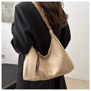 Detail of minimalist beige faux suede hobo bag with wide strap and brown drawstring charm