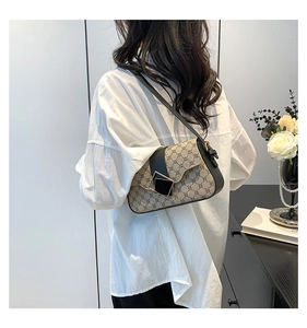 Nahaufnahme der Retro-Monogramm-Tasche mit goldener Schnalle an Model in weißem Hemd