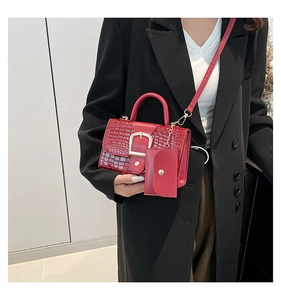 Detail of red crocodile texture handbag with metal buckle and mini pouch charm