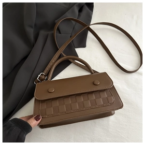 Detail of checkered pattern texture on brown leather crossbody bag with flap and buttons