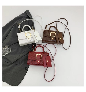 Détail à plat de sacs à main gaufrés croco en blanc, marron et rouge avec boucle en D doré