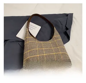 Detailed view of houndstooth wool fabric and brown leather straps on the tote bag