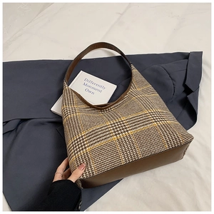 Close-up of vintage brown plaid fabric and leather stitching on the underarm bag