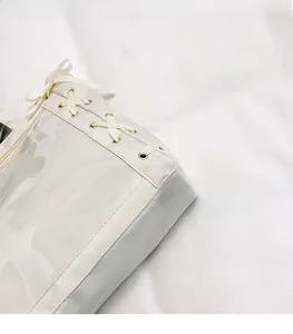 Dettaglio borsa bianca in nylon e PVC con occhielli metallici e lacci decorativi laterali