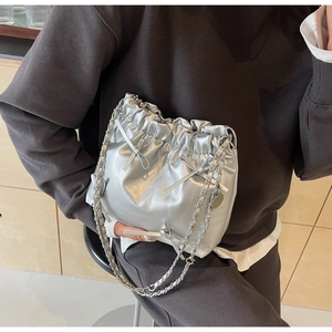 Close-up of silver metallic bucket bag featuring drawstring closure and bow detail