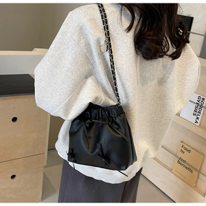 Detailed view of black matte leather bucket bag with ribbon bow and metal chain strap