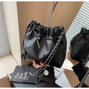 Detail of black pleated cloud bucket bag with silver chain strap and bow decoration