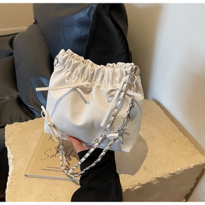 Detail of cream drawstring bucket bag featuring soft leather texture and bow detail