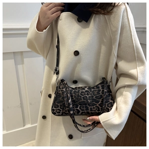 Détail du sac croissant à imprimé léopard avec bandoulière noire sur un manteau blanc