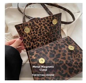 Macro shot of the magnetic gold-tone snap closure on a leopard print PU leather handbag