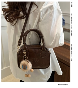 Detail view of dark brown bowling bag with bear charm and adjustable shoulder strap