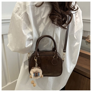 Detail der dunkelbraunen Vintage Boston Tasche mit Plüsch-Anhänger und Schultergurt