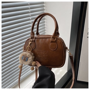 Detail der karamellbraunen Retro PU-Handtasche mit Lucky-Schriftzug und Plüschbär-Anhänger