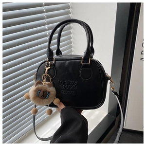 Detail der schwarzen Tasche mit LHCO Smu Prägung und braunem Plüschtier-Anhänger