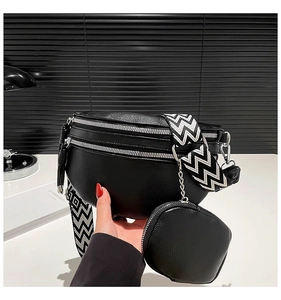 Close-up of black pebble leather crossbody bag with geometric pattern strap and small coin pouch