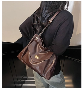 Detail of vintage brown tote bag with metallic chain strap and golden buckle clasp