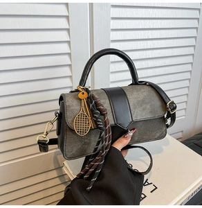 Détail du sac à main en denim gris avec garniture en cuir noir et breloque raquette dorée