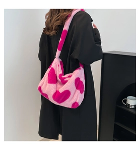 Nahaufnahme der rosa Plüsch-Tragetasche mit Herzmuster auf einer minimalistischen Schulter