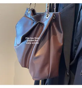 Détail d'un sac cabas marron foncé avec poche frontale à rabat et bandoulière chaîne