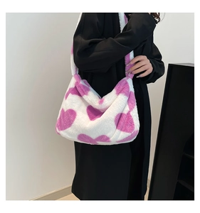 Close-up of fluffy faux fur shoulder bag with purple heart patterns on a white background