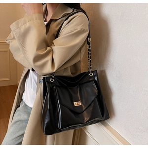 Detail view of a black PU leather tote bag with gold twist lock and metal chain strap