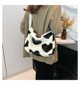 Detail of plush black and white heart tote bag on model showing soft texture and large capacity