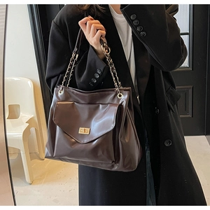 Close-up of a large dark brown tote bag with a gold metal chain strap and twist-lock