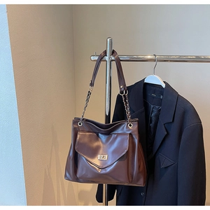 Detail of dark brown PU leather tote bag with gold metal twist lock and chain strap