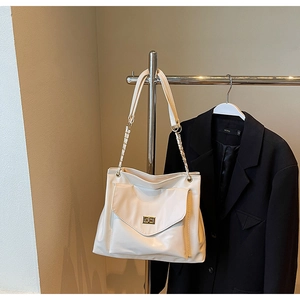 Detail of cream white PU leather tote with gold twist lock and chain strap on blazer