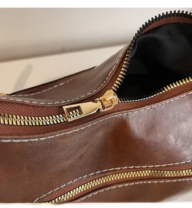 Détail de la fermeture éclair dorée et texture en cuir grainé marron du sac à main