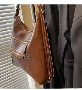 Détail du cabas en cuir marron avec fermetures éclair latérales et surpiqûres contrastées