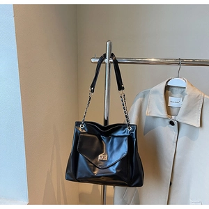 Detail of black PU leather tote bag featuring gold twist lock and metal chain strap