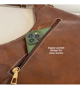 Détail du sac cabas en cuir marron avec poche zippée et smartphone vert