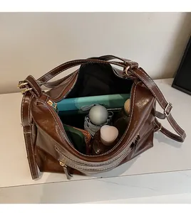 Vue intérieure d'un grand sac cabas marron foncé montrant tablette et objets quotidiens