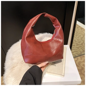 Close-up of brick red leather dumpling bag with unique geometric patchwork texture