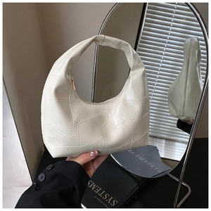 Detail of off-white faux leather handbag with irregular patchwork and pleated handle design