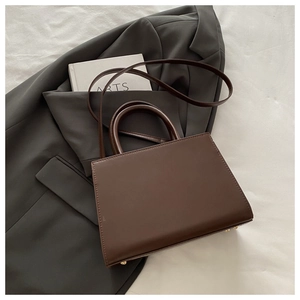Detail of minimalist coffee brown tote bag with matte finish and gold bottom studs