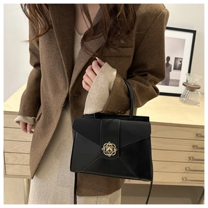 Detail of vintage black leather tote bag featuring a decorative golden flower metal buckle