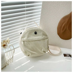 Detail of minimalist round nylon crossbody bag with top handle and adjustable strap