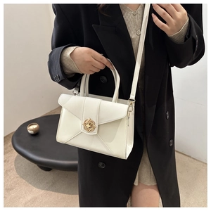 Detail of white leather crossbody bag featuring a vintage gold decorative buckle