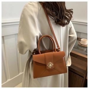 Rear view of model wearing a vintage brown matte leather tote with floral gold buckle